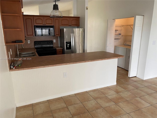 kitchen featuring washer and clothes dryer, black appliances, sink, hanging light fixtures, and light tile patterned floors