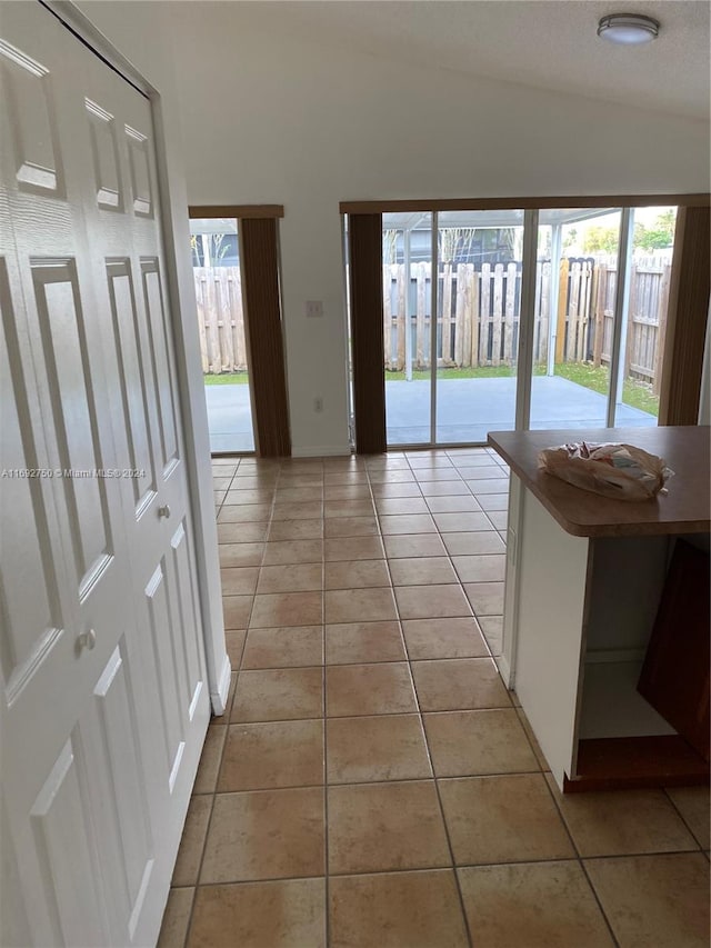 corridor featuring lofted ceiling, a textured ceiling, and light tile patterned floors