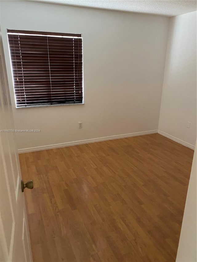 unfurnished room featuring wood-type flooring and a textured ceiling