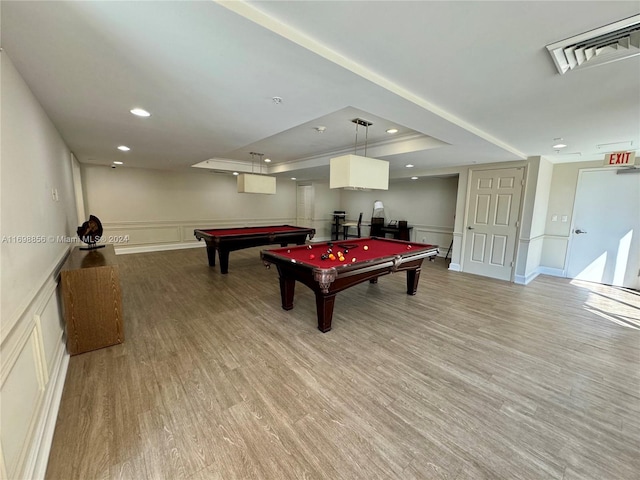 game room featuring light hardwood / wood-style floors, a raised ceiling, and pool table