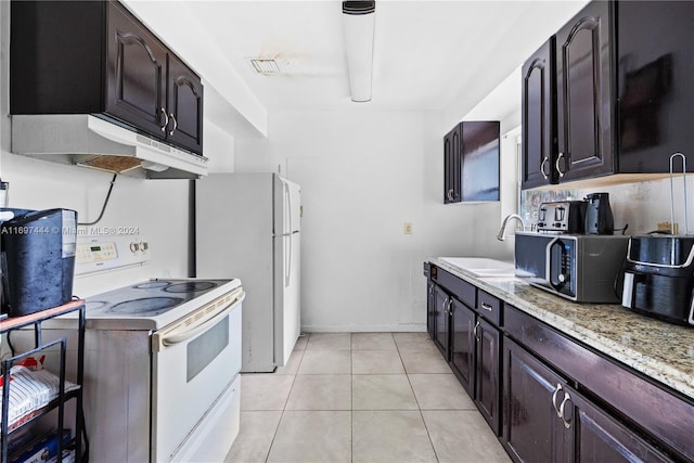 kitchen featuring sink, light stone counters, white appliances, dark brown cabinets, and light tile patterned flooring