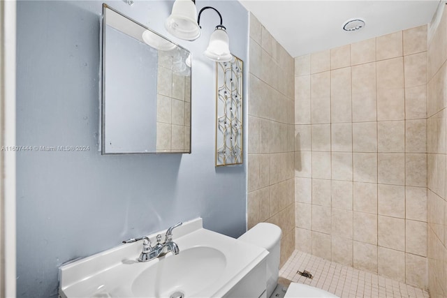 bathroom featuring a tile shower, vanity, and toilet