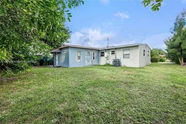 rear view of property with central AC and a yard