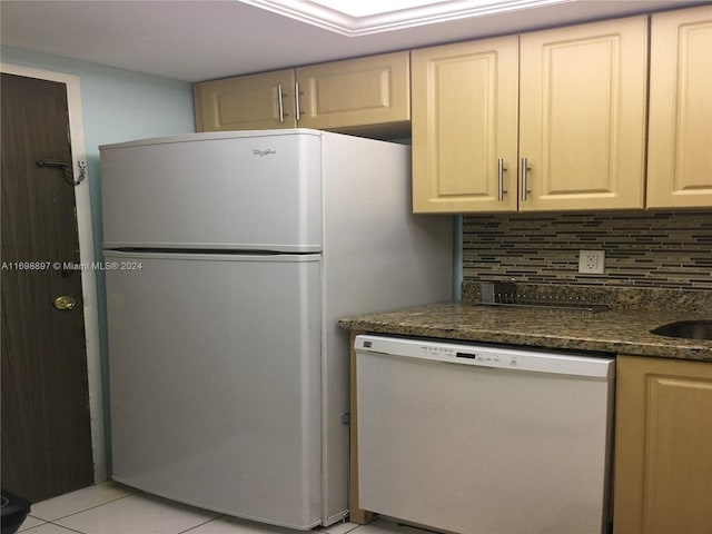 kitchen with dark stone countertops, white appliances, backsplash, and light tile patterned floors