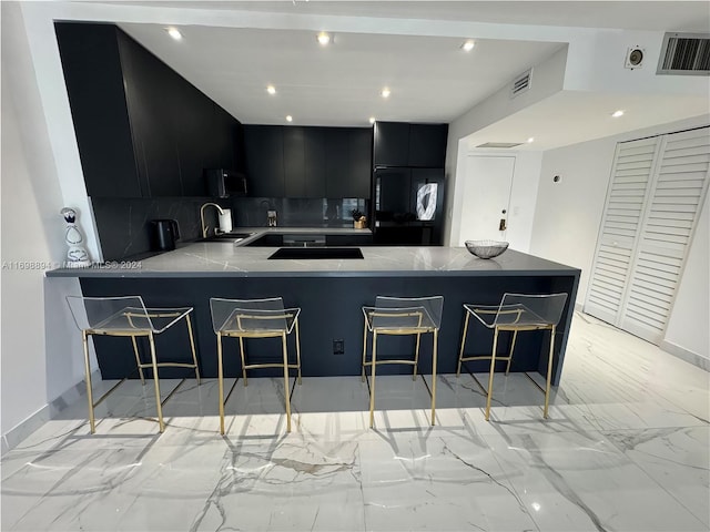 kitchen featuring a kitchen breakfast bar, kitchen peninsula, backsplash, and sink