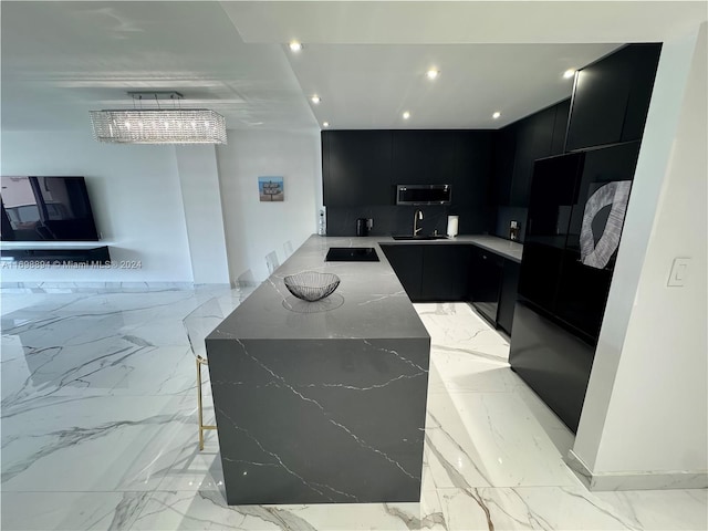 kitchen featuring a breakfast bar area, black electric cooktop, light stone counters, and sink