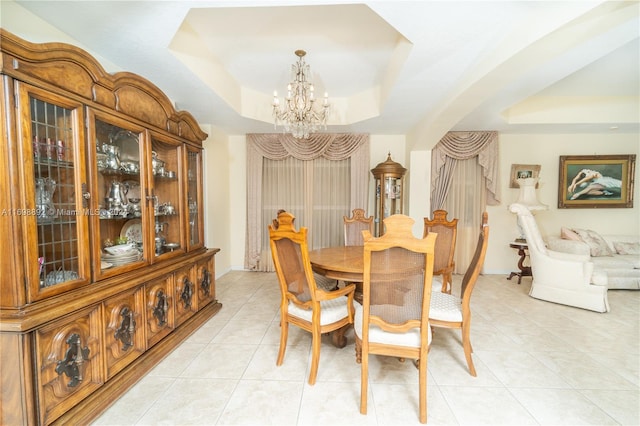 dining space with a notable chandelier, light tile patterned floors, and a tray ceiling