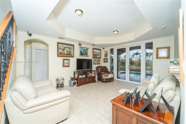 living room featuring light tile patterned flooring, a raised ceiling, and french doors