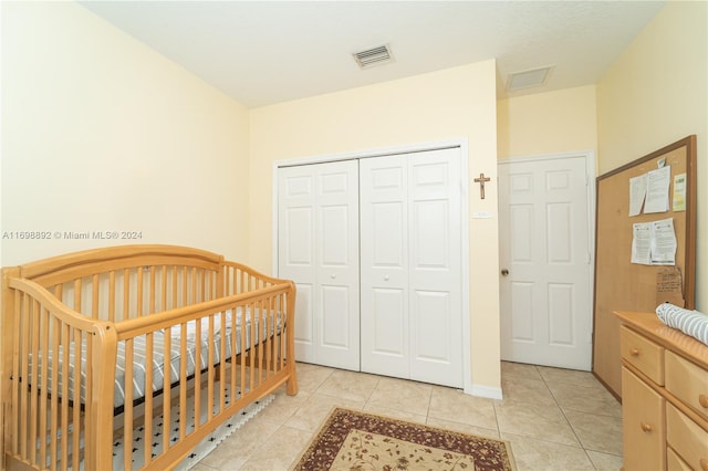 bedroom with a closet, a nursery area, and light tile patterned flooring