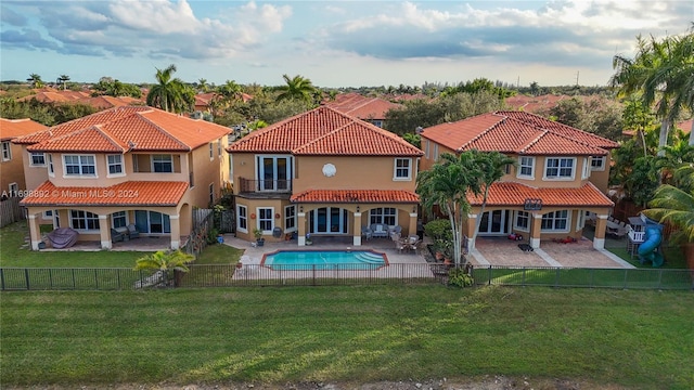 back of house featuring a fenced in pool, a yard, and a patio