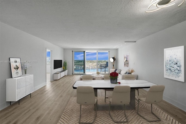 dining space with light wood-type flooring and a textured ceiling