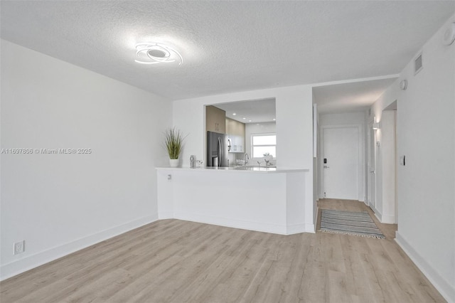 unfurnished living room with a textured ceiling and light hardwood / wood-style floors