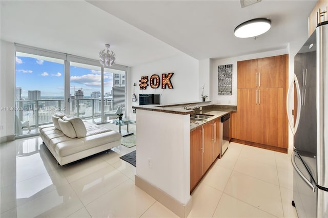 kitchen featuring dishwasher, a peninsula, brown cabinetry, and freestanding refrigerator