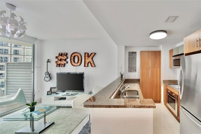 kitchen with kitchen peninsula, light tile patterned floors, stainless steel appliances, and sink