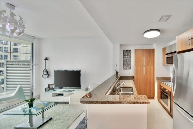 kitchen featuring light tile patterned floors, sink, stainless steel appliances, and stone countertops