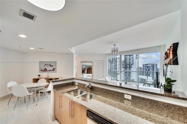 kitchen featuring dishwasher, light brown cabinets, sink, and dark stone counters