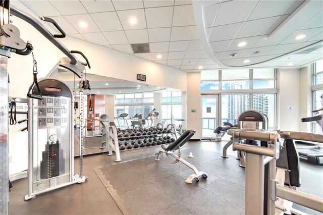 gym with a paneled ceiling, a wealth of natural light, and a high ceiling