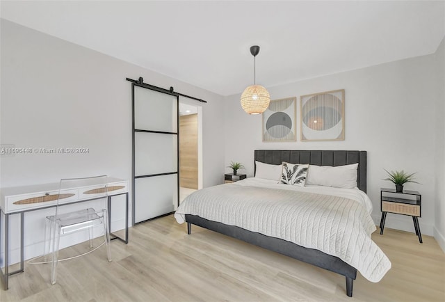 bedroom with a barn door and wood-type flooring