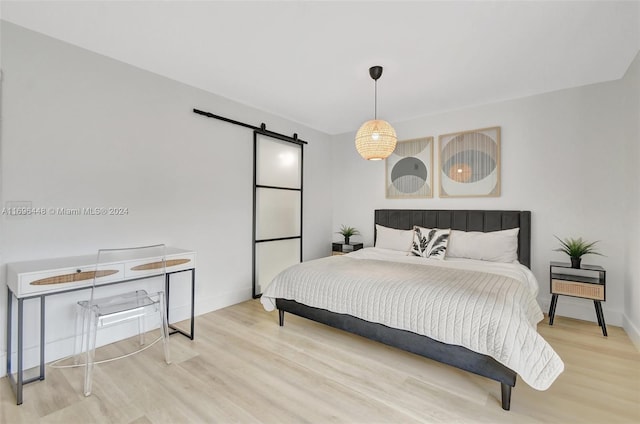 bedroom featuring a barn door and wood-type flooring