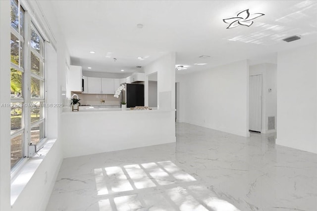 interior space featuring kitchen peninsula, white cabinetry, and black refrigerator