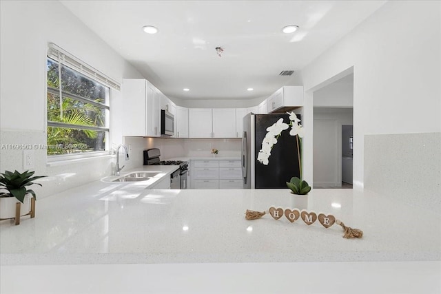 kitchen with appliances with stainless steel finishes, white cabinetry, and sink