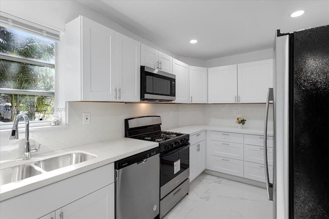 kitchen with tasteful backsplash, white cabinetry, sink, and appliances with stainless steel finishes