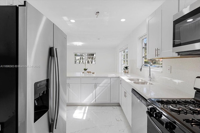 kitchen with sink, appliances with stainless steel finishes, tasteful backsplash, white cabinetry, and kitchen peninsula