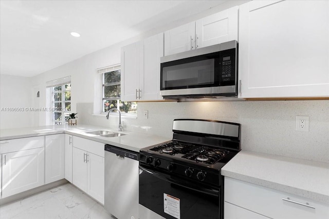 kitchen featuring backsplash, white cabinetry, sink, and appliances with stainless steel finishes