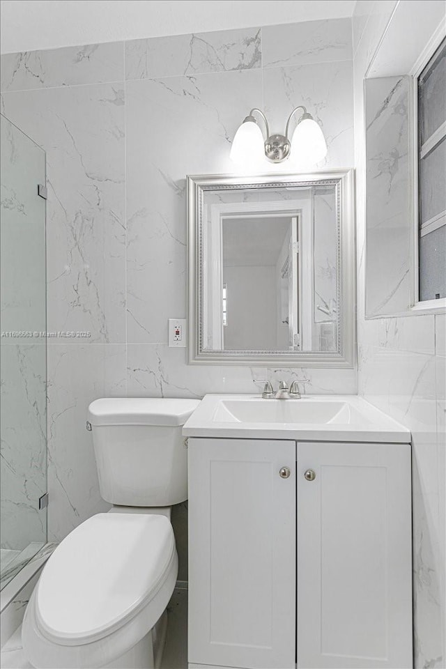 bathroom featuring vanity, toilet, and tile walls