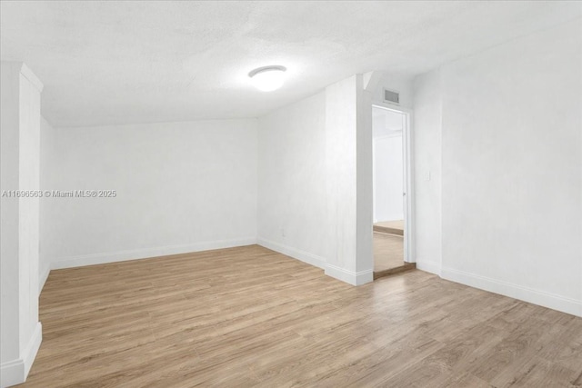 empty room featuring a textured ceiling and light wood-type flooring