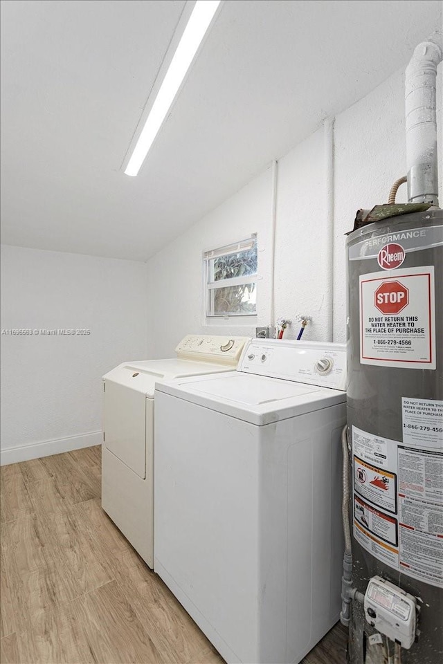 washroom with washing machine and clothes dryer, light wood-type flooring, and water heater