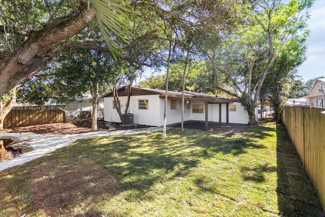 back of property with central AC and a yard