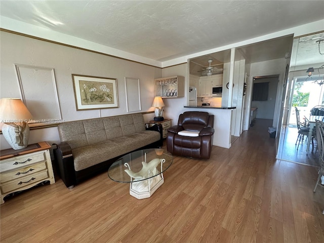 living room with a textured ceiling, light hardwood / wood-style flooring, and ceiling fan