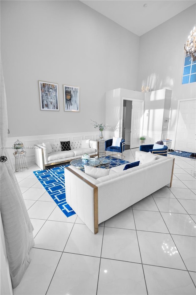 tiled living room with a high ceiling, an inviting chandelier, and tile walls