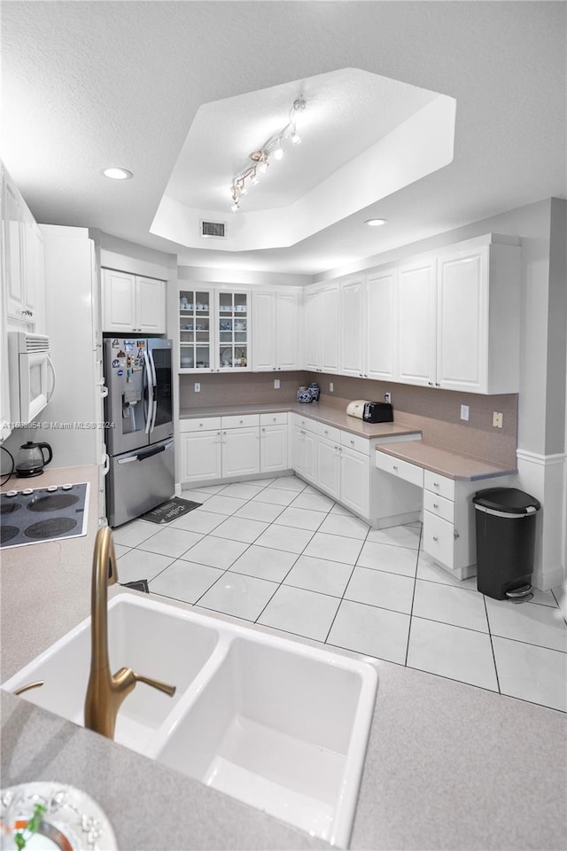 kitchen with white cabinets, electric cooktop, a raised ceiling, stainless steel fridge, and light tile patterned flooring