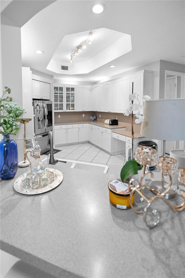 kitchen featuring white cabinetry, a raised ceiling, stainless steel fridge with ice dispenser, and light tile patterned floors