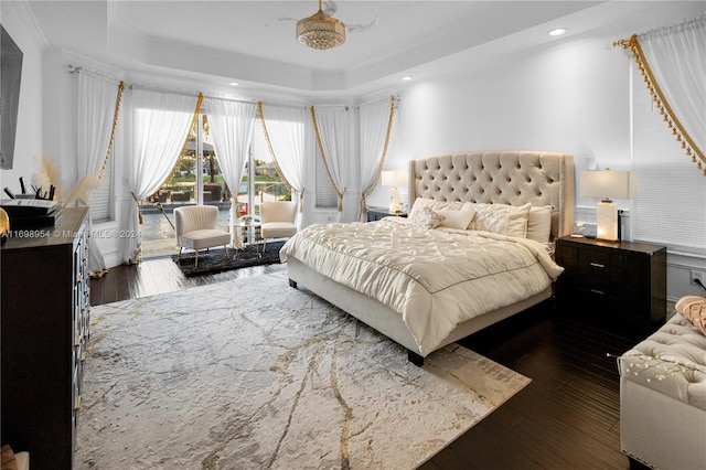 bedroom featuring a raised ceiling, dark hardwood / wood-style floors, and ornamental molding