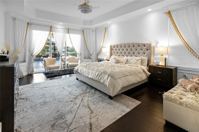 bedroom with a raised ceiling, access to exterior, and dark wood-type flooring