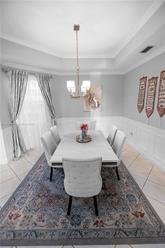 tiled dining area with a chandelier, a raised ceiling, and crown molding