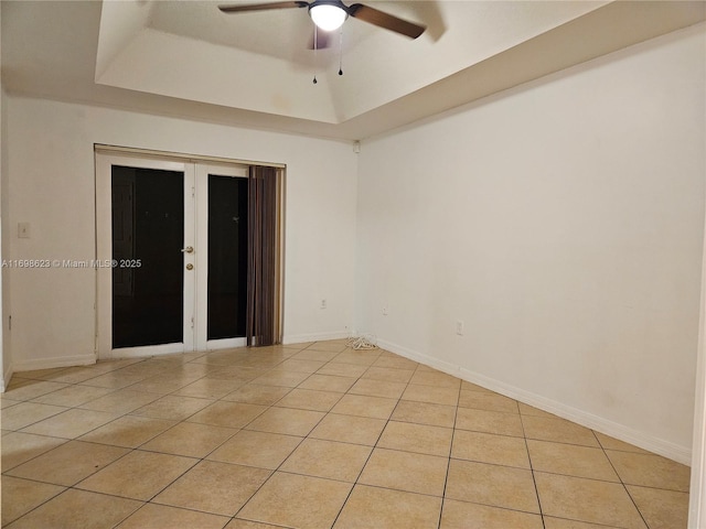 unfurnished room featuring light tile patterned floors, ceiling fan, and a tray ceiling