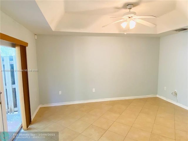 spare room featuring ceiling fan, a tray ceiling, and light tile patterned floors