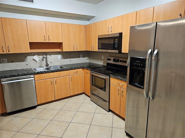 kitchen featuring light tile patterned floors, backsplash, appliances with stainless steel finishes, dark stone countertops, and sink