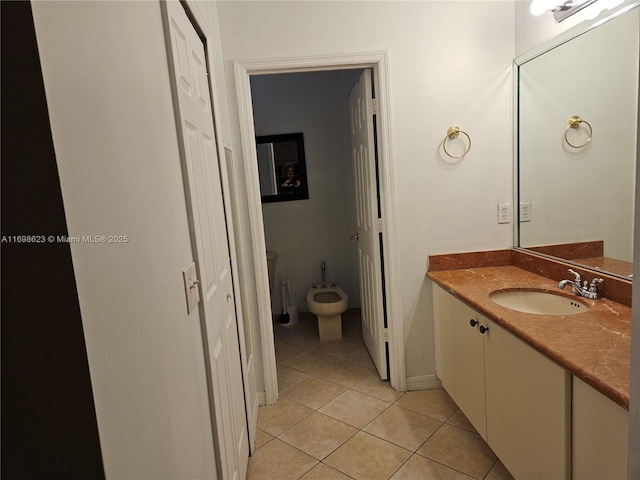 bathroom featuring toilet, tile patterned floors, vanity, and a bidet