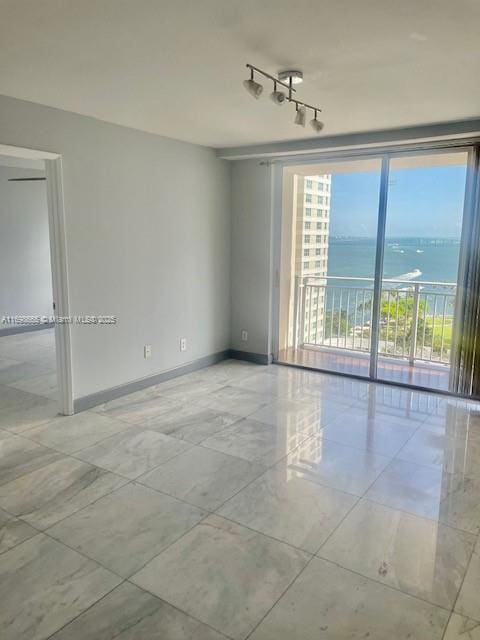 unfurnished room featuring rail lighting and a water view