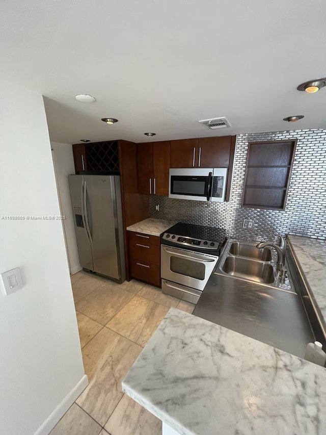 kitchen with tasteful backsplash, appliances with stainless steel finishes, sink, and dark brown cabinets