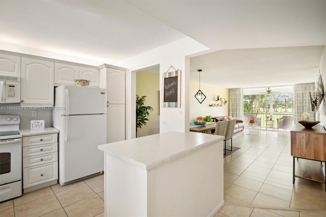 kitchen featuring white cabinets, hanging light fixtures, a center island, light tile patterned floors, and white appliances