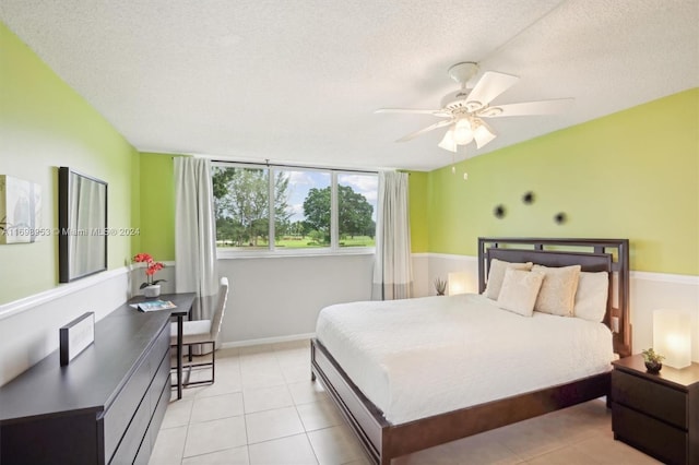 bedroom featuring ceiling fan, light tile patterned floors, and a textured ceiling