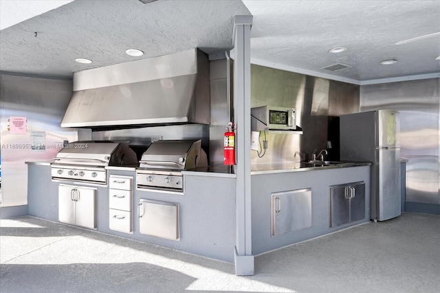 kitchen with stainless steel fridge, sink, a textured ceiling, and wall chimney range hood