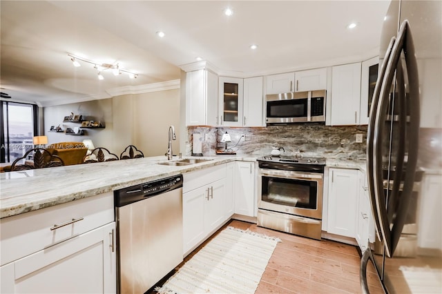 kitchen featuring light stone countertops, light wood-type flooring, stainless steel appliances, sink, and white cabinets