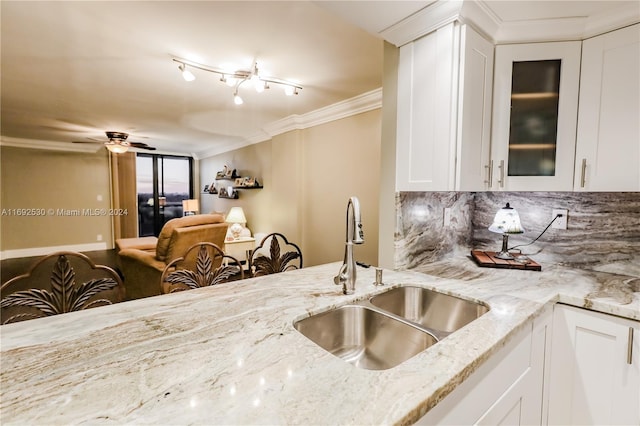 kitchen with backsplash, sink, ceiling fan, light stone counters, and white cabinetry